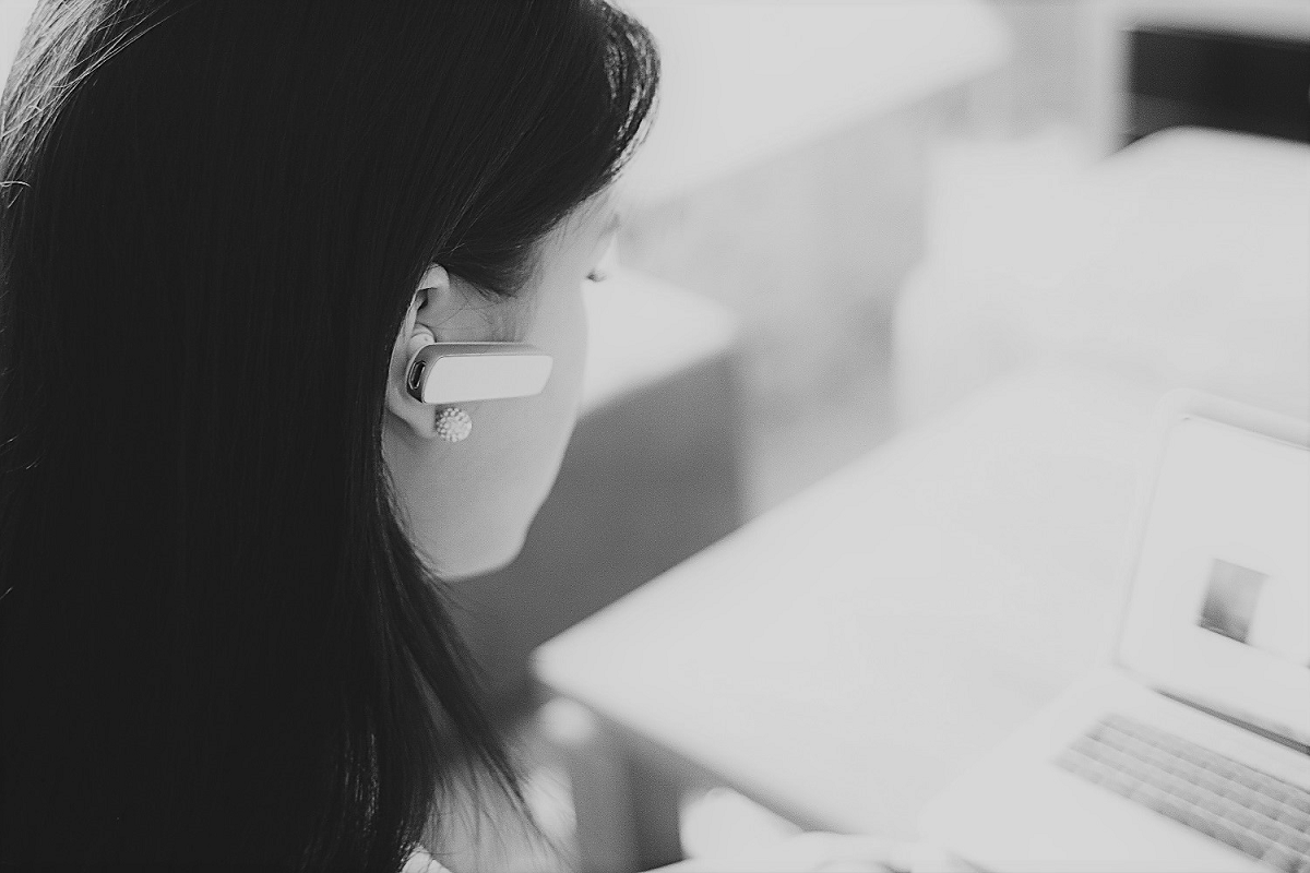 Woman with bluetooth headset working on laptop