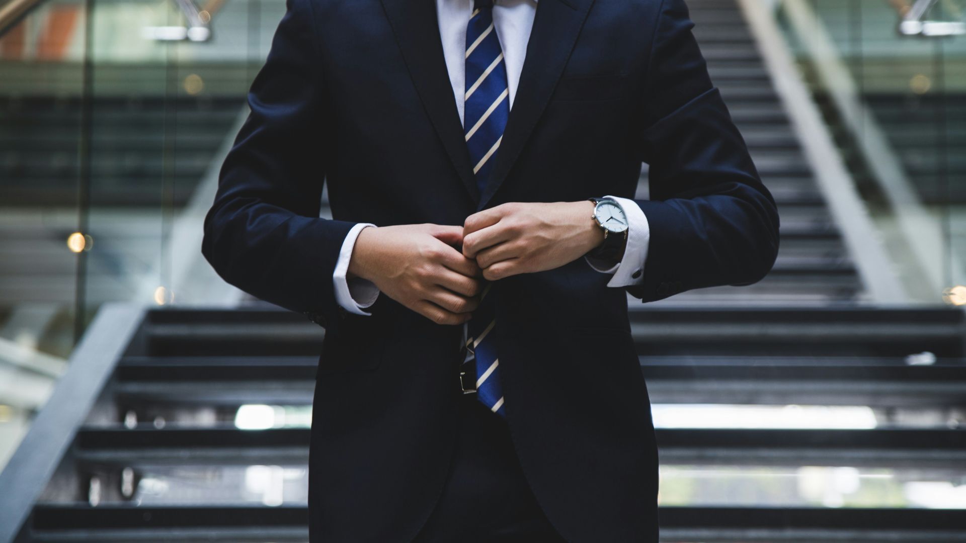 A smartly dressed businessman fastening his suit jacket