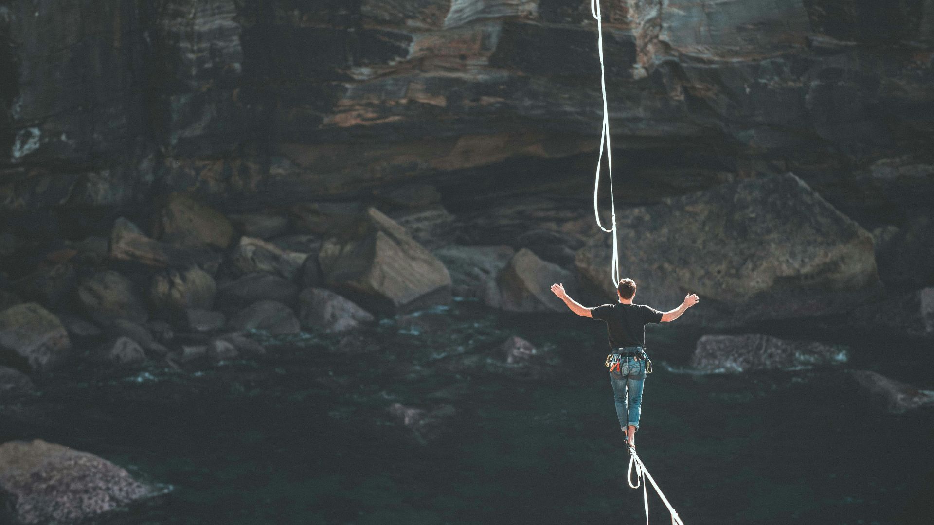 A tightrope walker on a rope over a dark canyon
